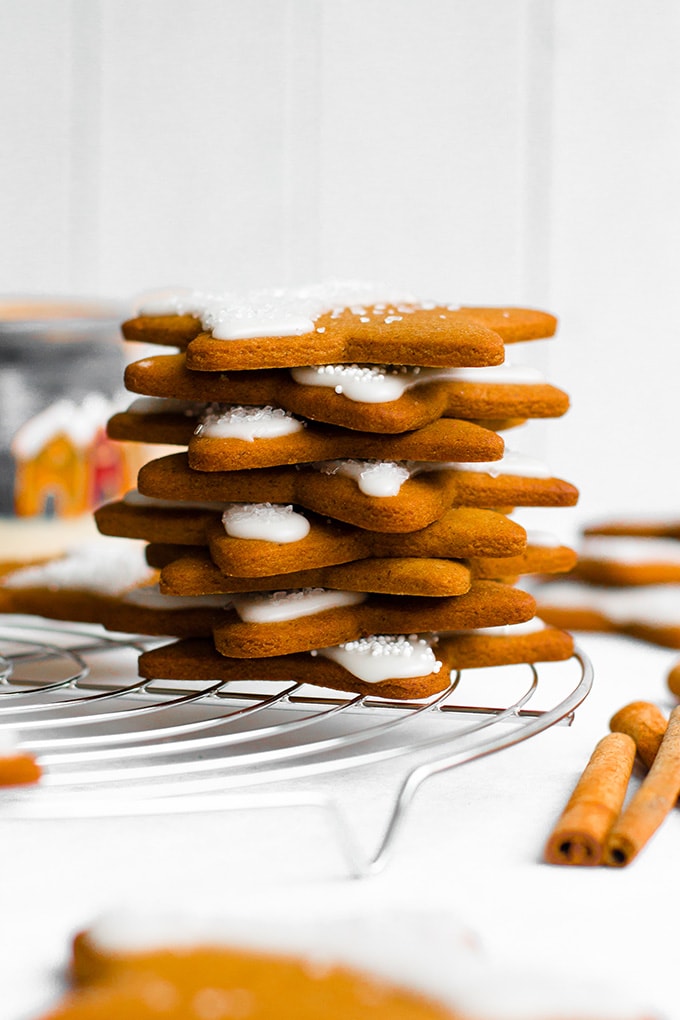 Gingerbread star cookies stacked in a tower on top of a silver, round cooling rack.