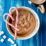A bowl full of classic hot cocoa mix, layered with peppermint candy canes in a heart shape.