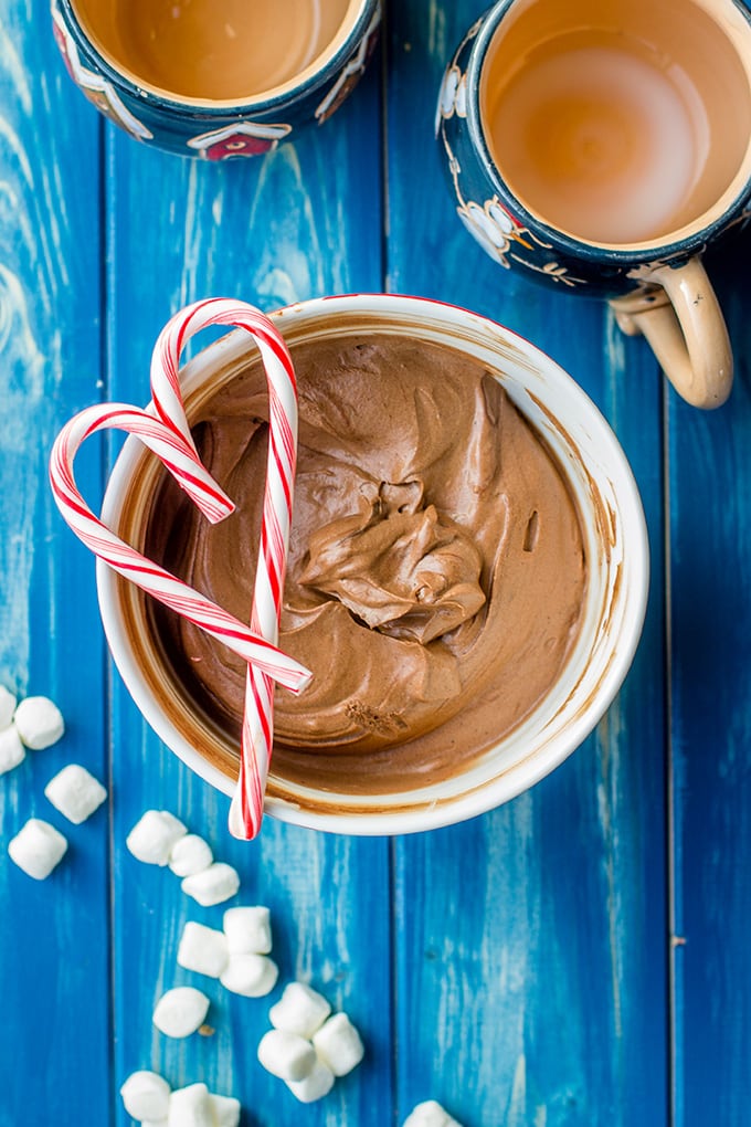 A bowl full of classic hot cocoa mix, layered with peppermint candy canes in a heart shape.