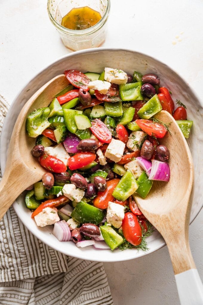 Large white ceramic bowl holding a Greek salad with homemade dressing.