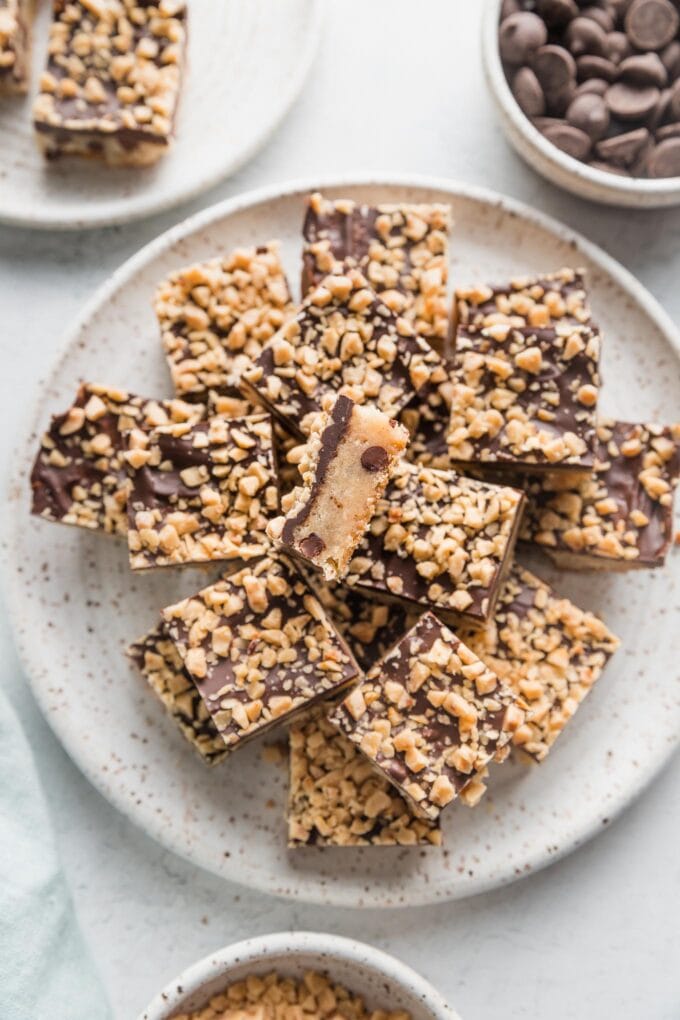 Plate of chocolate coated shortbread toffee cookie bars, with one turned to show the layers.