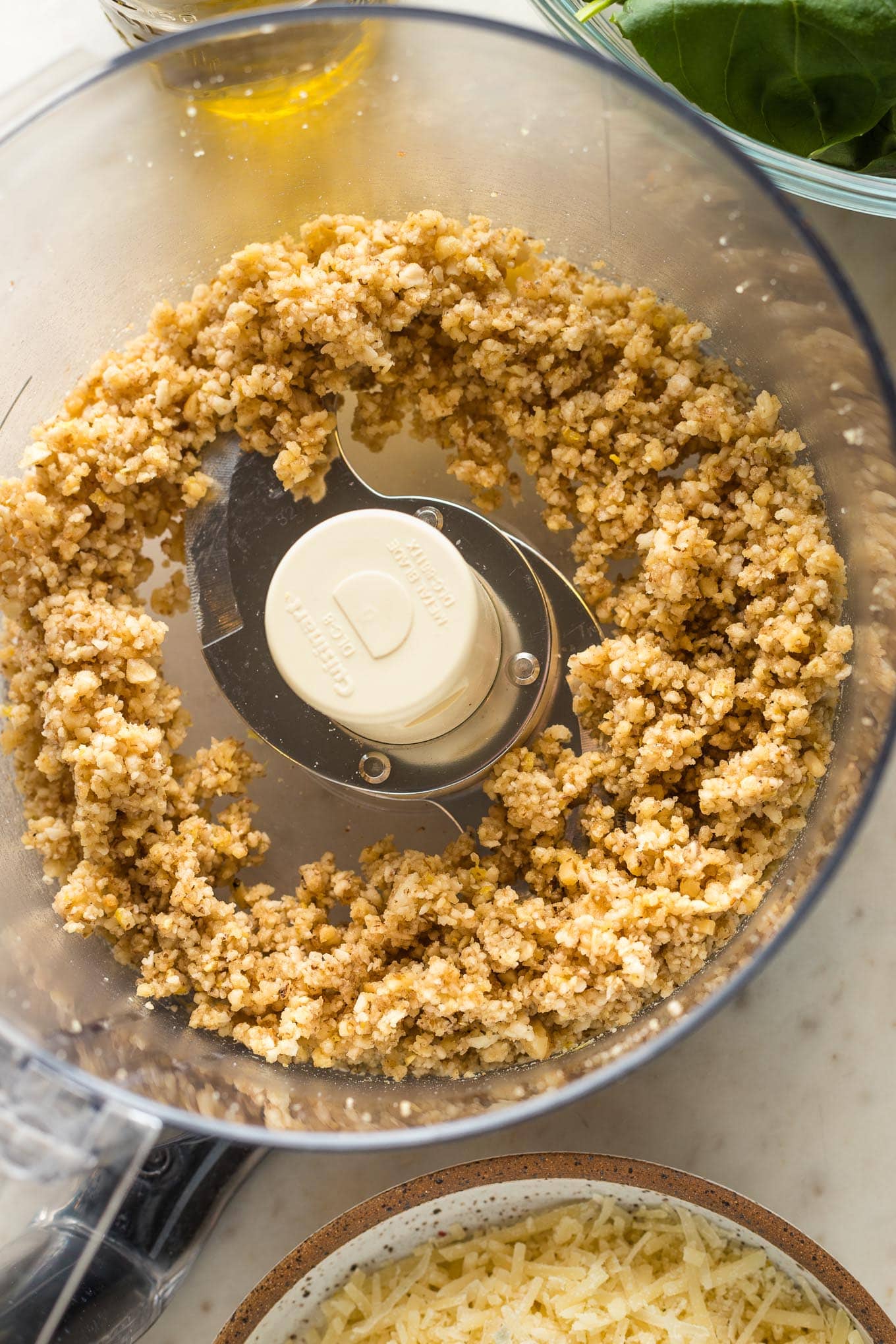 Chopped pine nuts, walnuts, and garlic in the bowl of a large food processor.