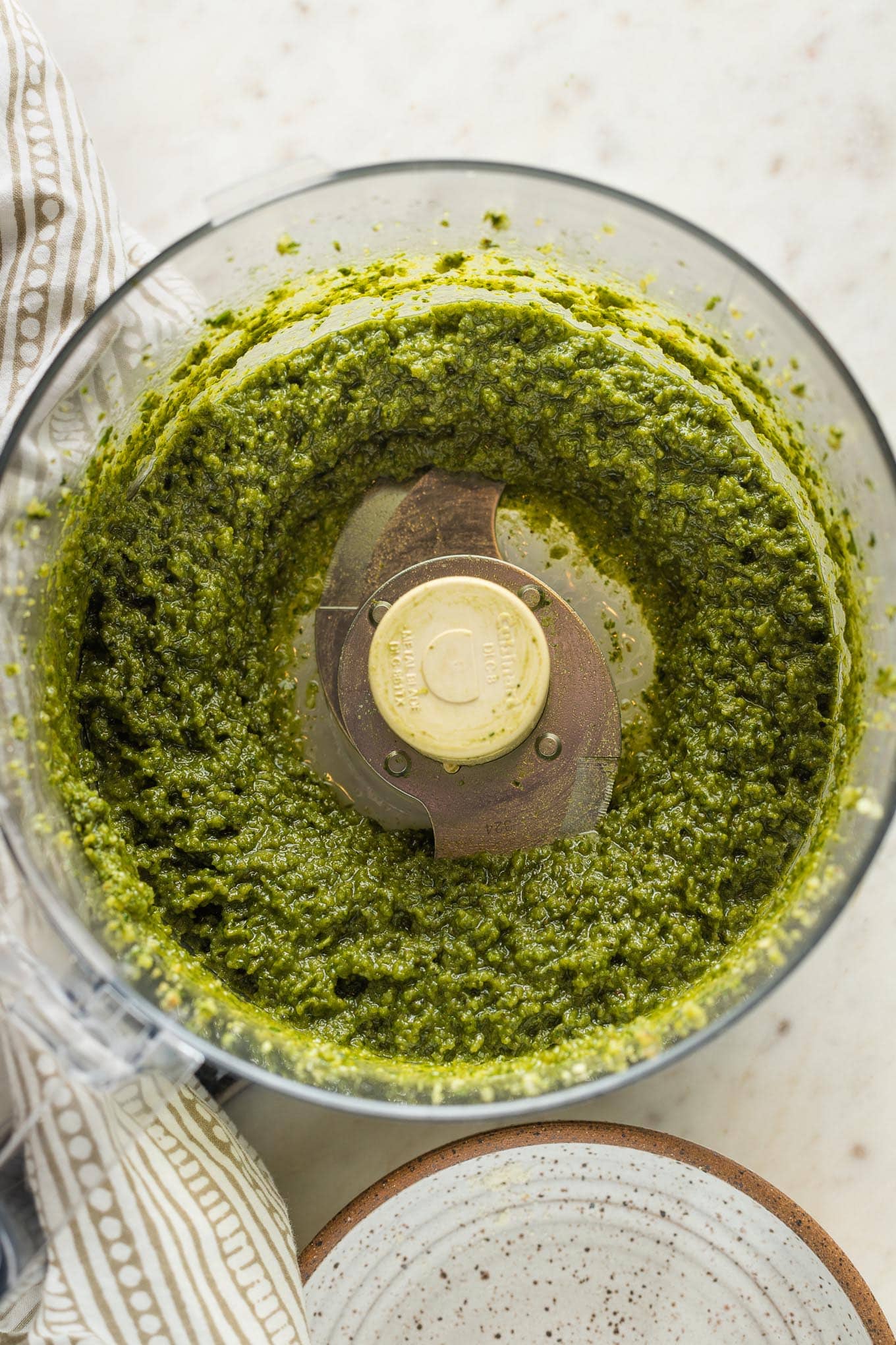 Smooth basil pesto with lemon in the bowl of a large food processor.