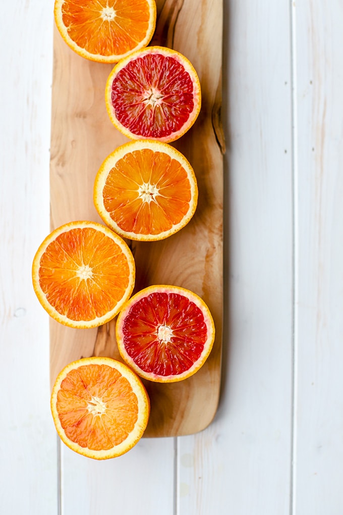 Brilliant pink and red blood oranges, sliced open and arrayed on a narrow cutting board.