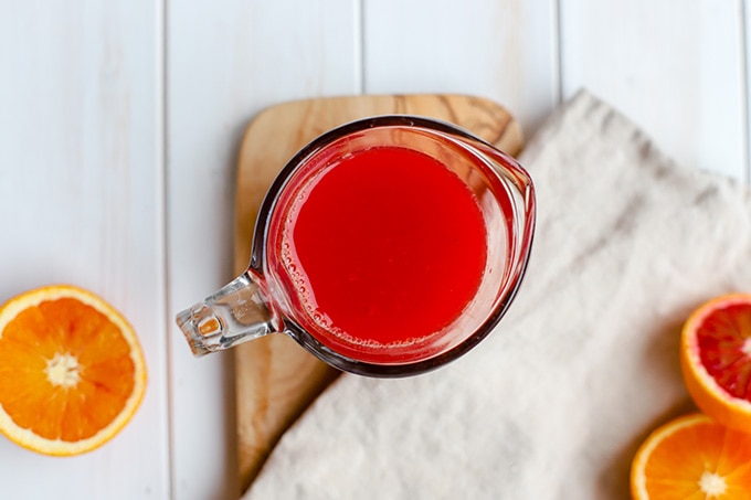 A measuring cup filled with freshly-squeezed blood orange juice.