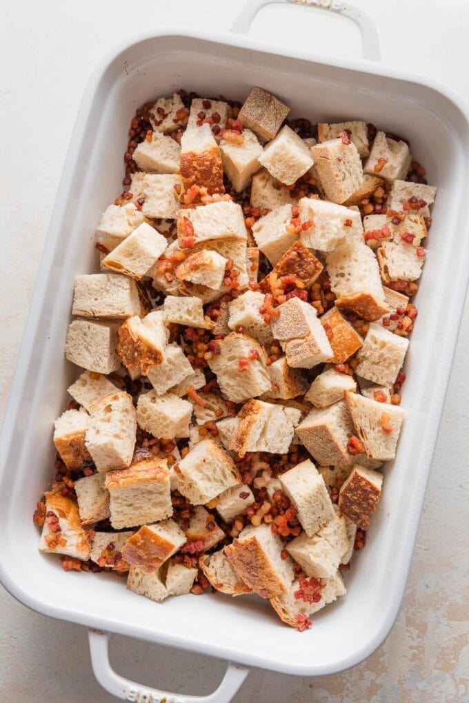 Crisped pancetta spread over bread cubes in a pan.