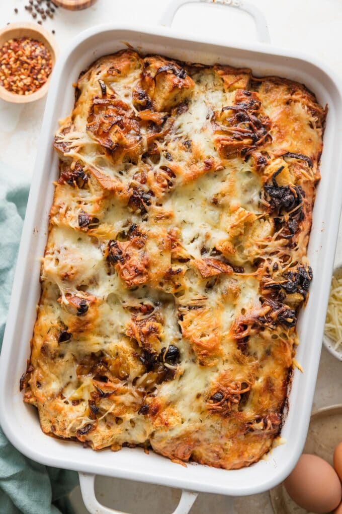 Deep 9x13-inch pan full of a breakfast strata with pancetta and caramelized onions.