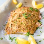 A large piece of salmon baked and coated with a crunchy mustard-panko crust, sliced into 3 sections.