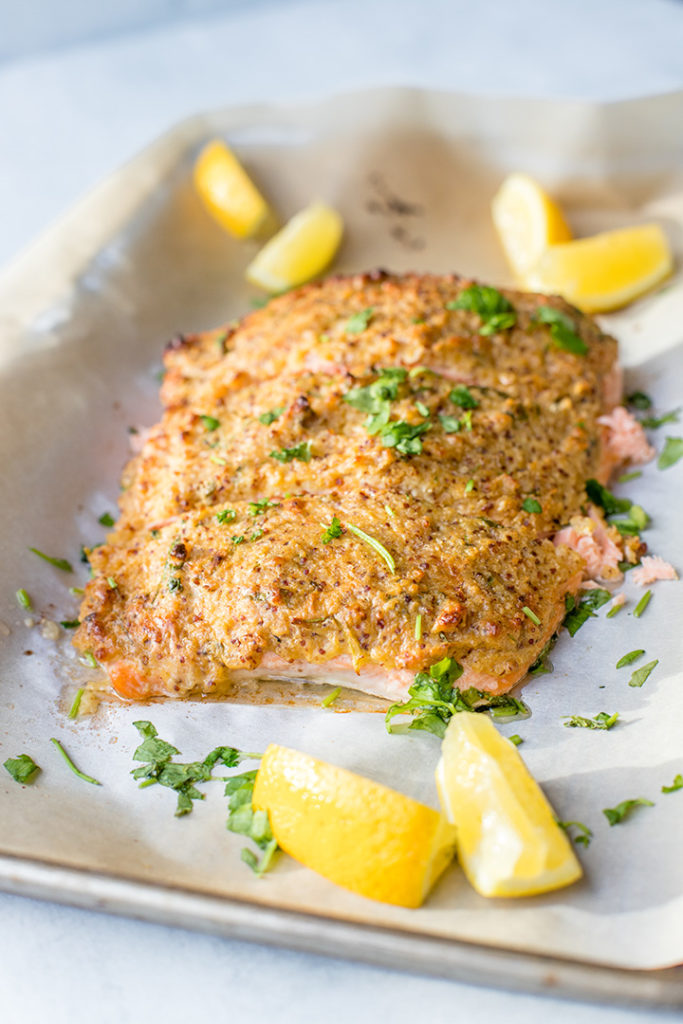 A large piece of salmon baked and coated with a crunchy mustard-panko crust, sliced into 3 sections.