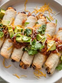 Close up chicken black bean taquitos piled onto a serving plate.