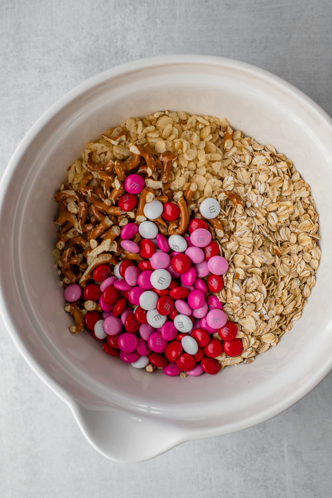 The dry ingredients for M&M pretzel granola bars, in a white mixing bowl ready to be stirred.