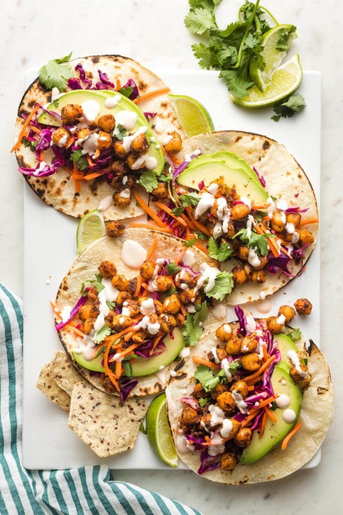 Crispy chickpea tacos with sunset slaw and a creamy sauce arranged on a serving tray.