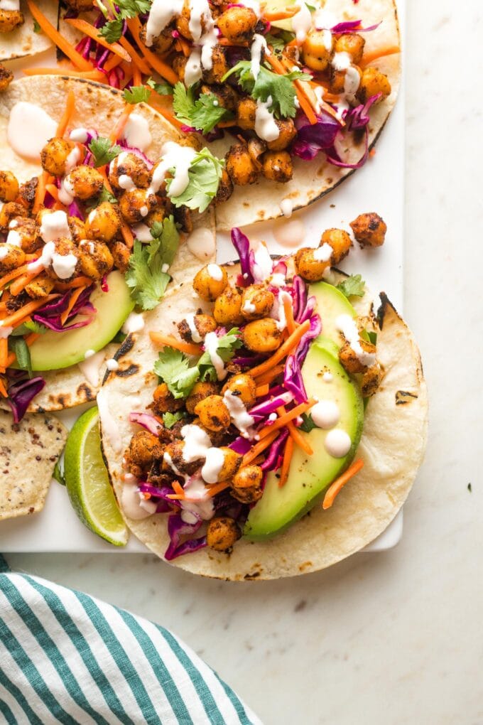 Crispy chickpea tacos with sunset slaw and a creamy sauce arranged on a serving tray.