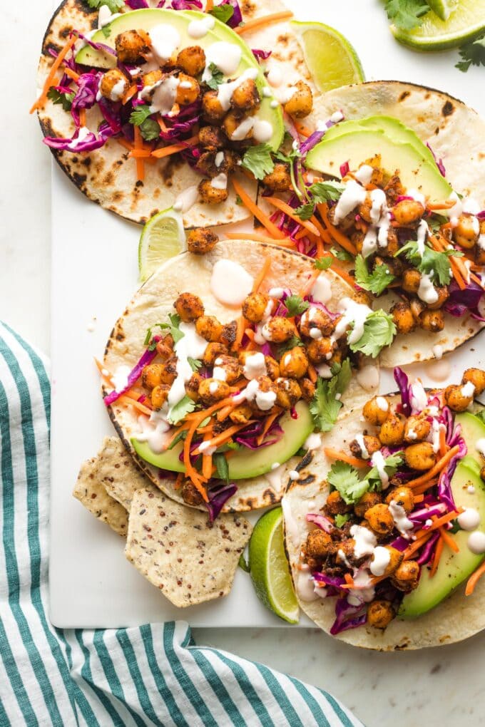 Crispy chickpea tacos with sunset slaw and a creamy sauce arranged on a serving tray.