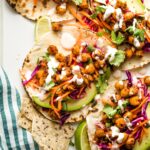 Crispy chickpea tacos with sunset slaw and a creamy sauce arranged on a serving tray.