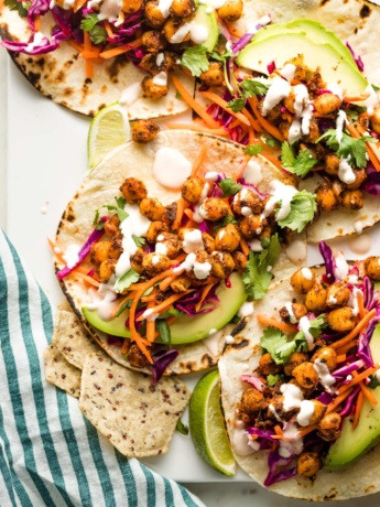 Crispy chickpea tacos with sunset slaw and a creamy sauce arranged on a serving tray.