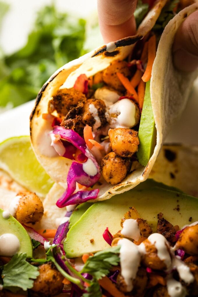 Close up of a hand picking up a taco with chickpeas and cabbage slaw.