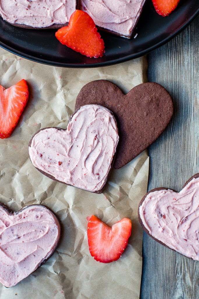 Two chocolate sugar cookies, semi-frosted.