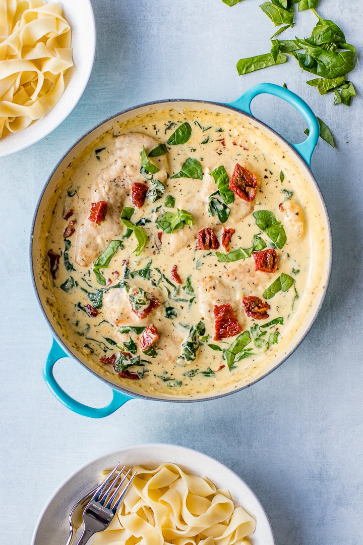 A small coated cast iron skillet filled with creamy Tuscan chicken, just cooked.