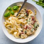 Close-up of a bowl filled with fresh pasta and creamy Tuscan chicken.