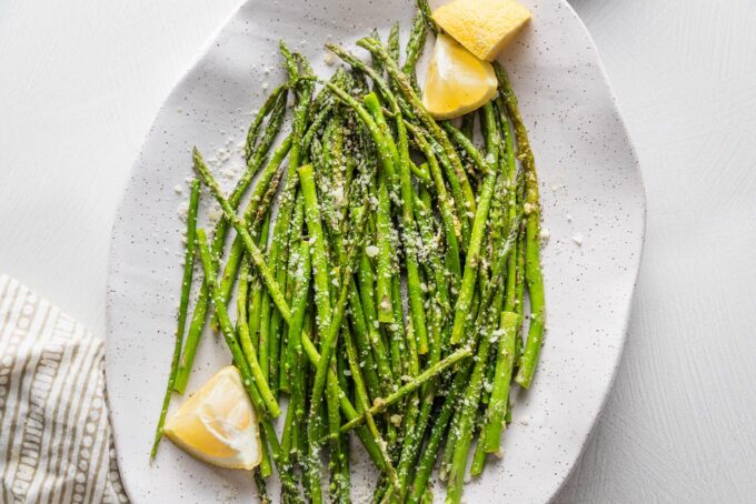 Close up of lemon asparagus roasted and served on a white platter.