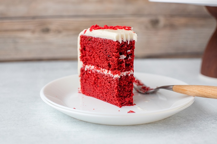 A slice of red velvet cake with cream cheese frosting.