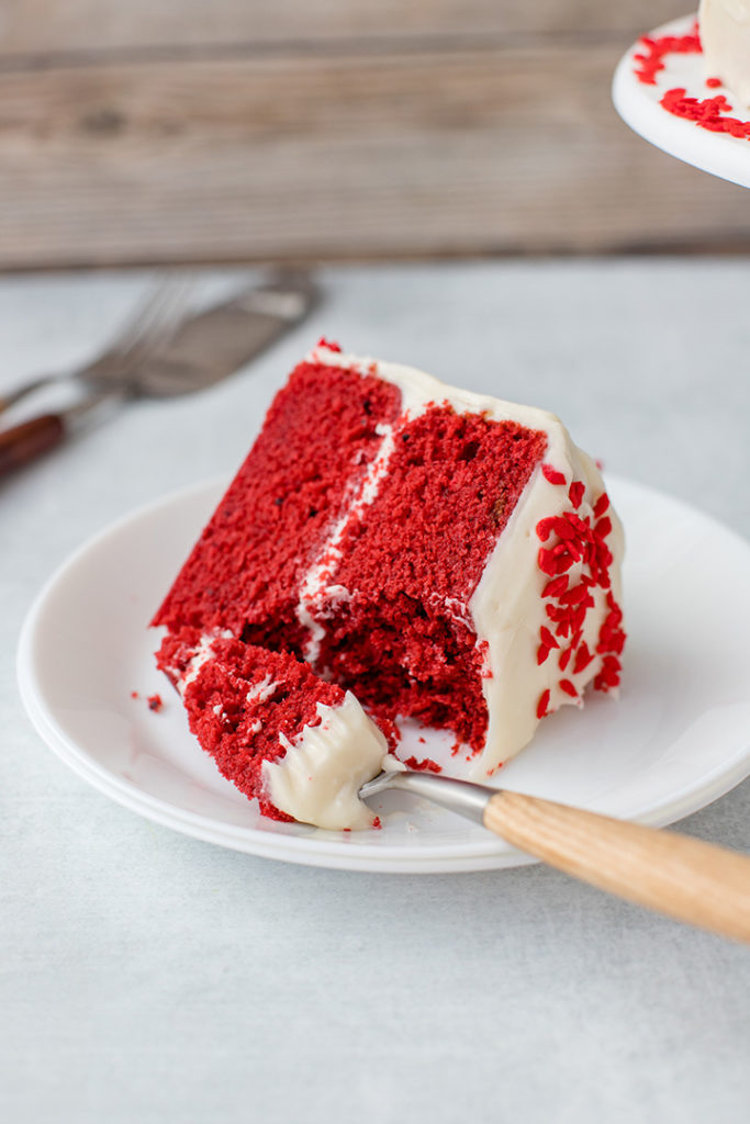A slice of red velvet cake with a generous forkful removed.