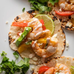 Close up of a sheet pan shrimp fajita with pepper, onion, and chipotle lime crema.