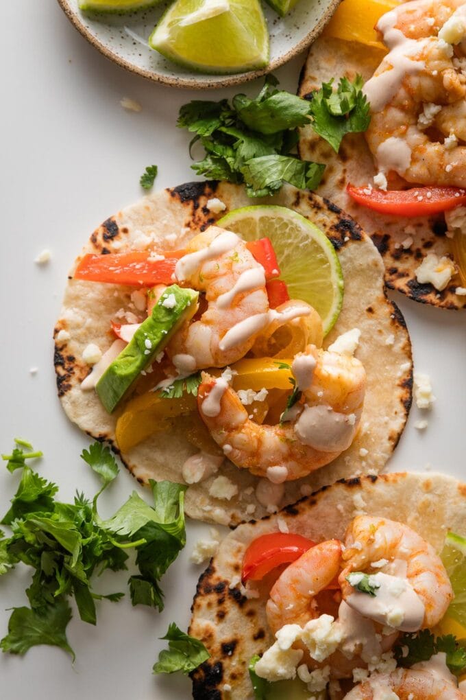 Close up of a sheet pan shrimp fajita with pepper, onion, and chipotle lime crema.