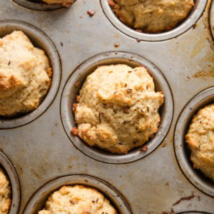 Close up of soda bread muffins baked with caraway seeds, still in the metal pan in which they were baked.