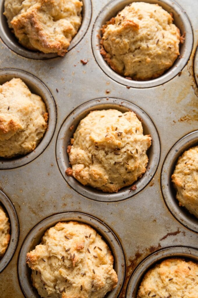 Close up of soda bread muffins baked with caraway seeds, still in the metal pan in which they were baked.