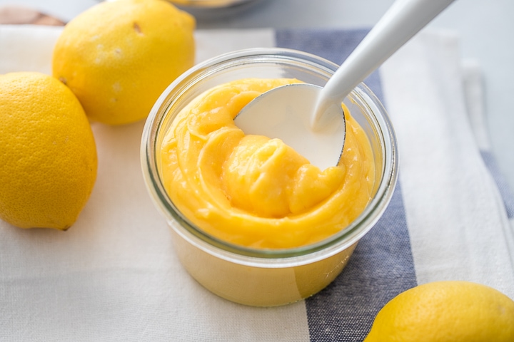 A small glass jar filled with thick, creamy, bright yellow homemade lemon curd.