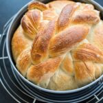 A just-baked loaf of homemade paska, the traditional Slovak Easter bread, still in the pan and resting on a cooling rack.