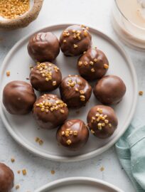 Small plate of Oreo truffles made with Irish cream instead of cream cheese, coated in milk chocolate and decorated with gold sprinkles.
