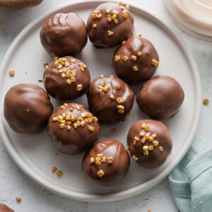 Small plate of Oreo truffles made with Irish cream instead of cream cheese, coated in milk chocolate and decorated with gold sprinkles.