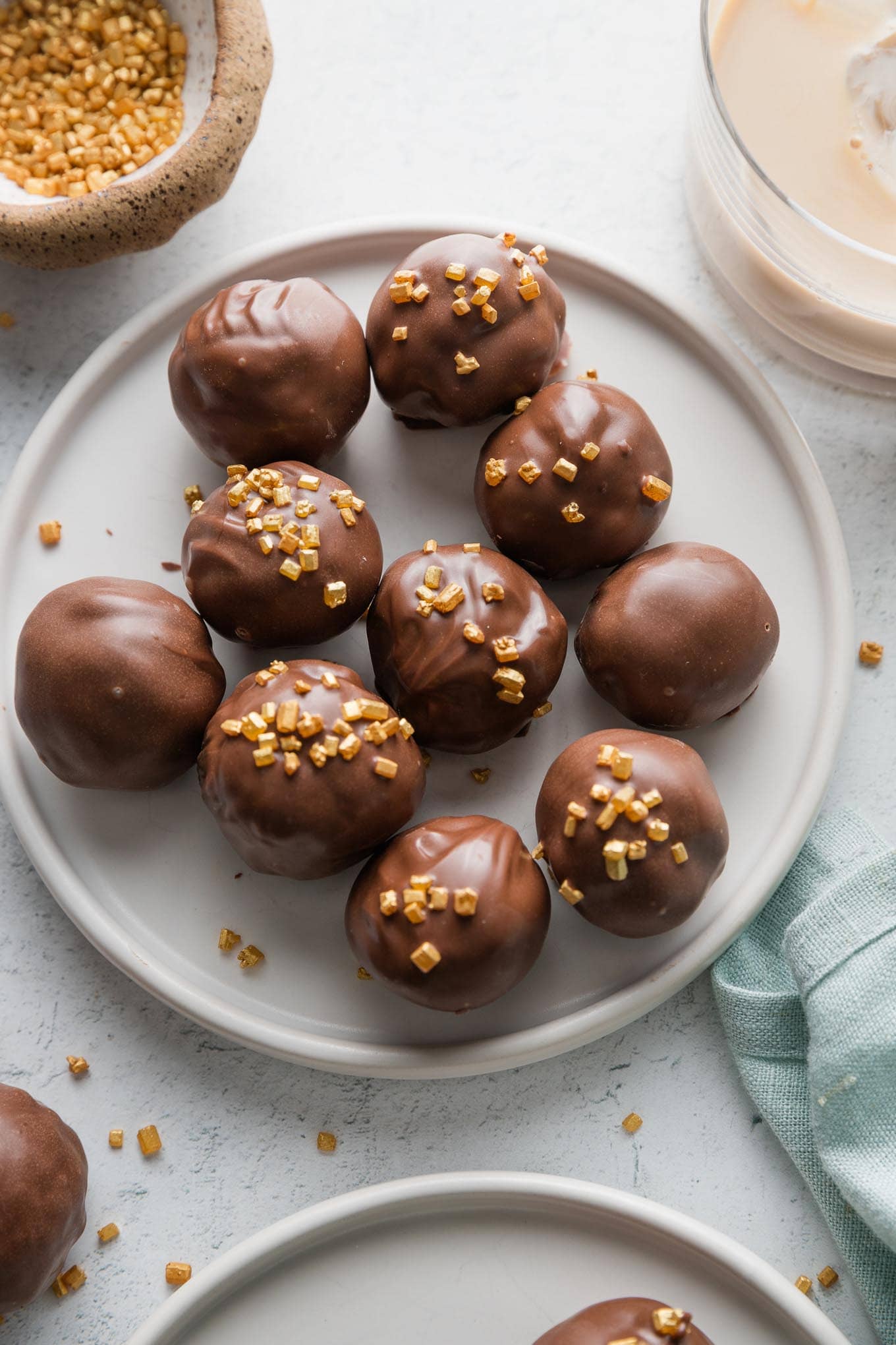 Small plate of Oreo truffles made with Irish cream instead of cream cheese, coated in milk chocolate and decorated with gold sprinkles.
