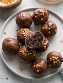 Plate of Oreo truffles made with Irish cream instead of cream cheese, with one open to reveal the dark chocolate interior.