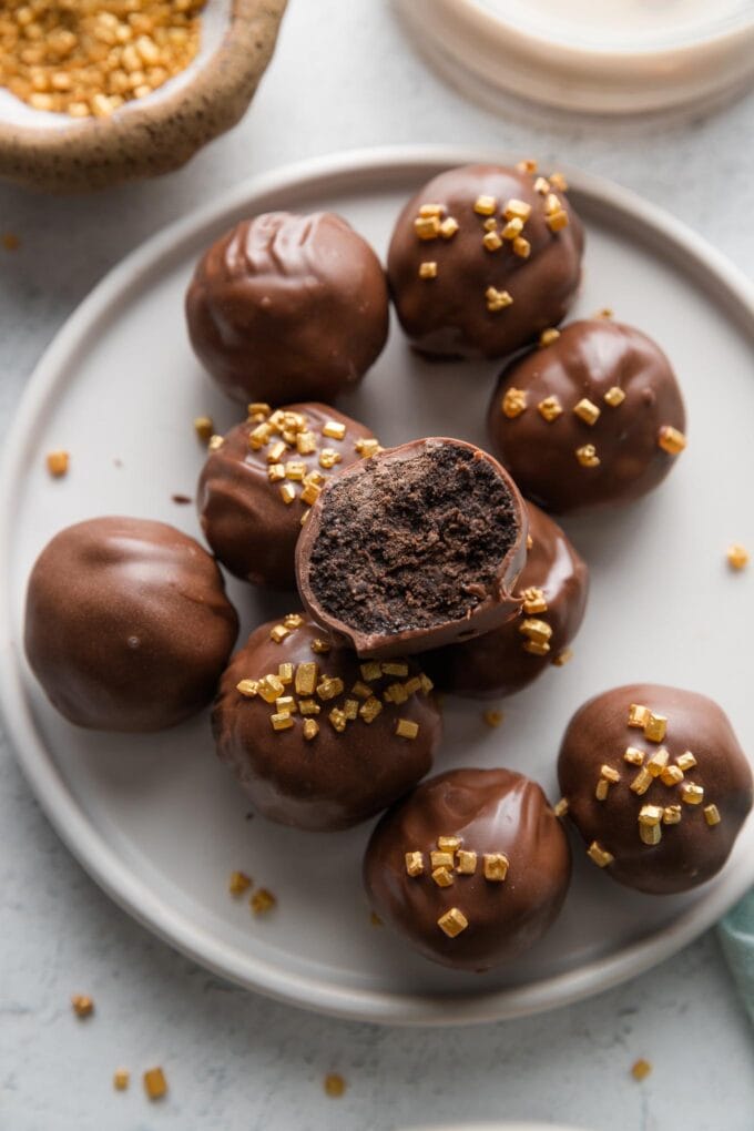 Plate of Oreo truffles made with Irish cream instead of cream cheese, with one open to reveal the dark chocolate interior.