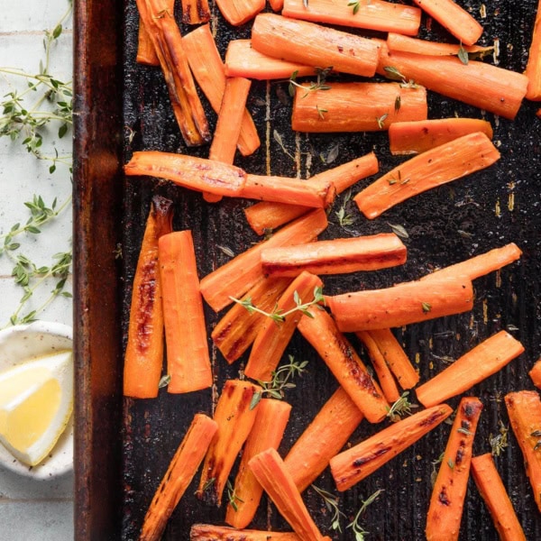Small sheet pan with roasted whole carrots with butter, salt, pepper, and thyme.