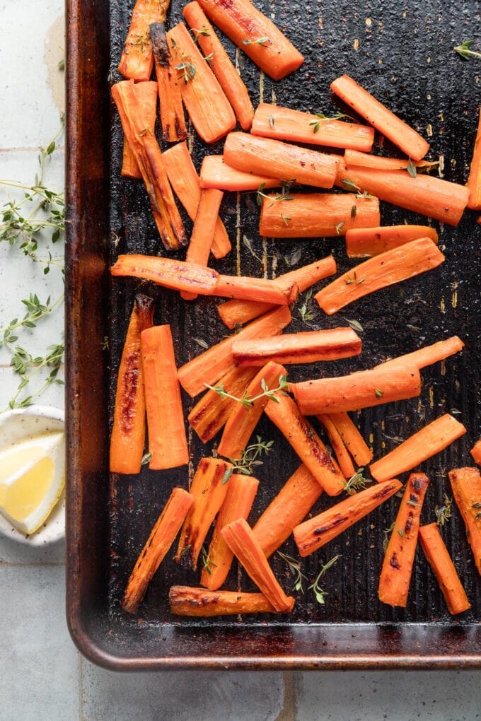 Small sheet pan with roasted whole carrots with butter, salt, pepper, and thyme.