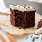 A small square slice of Mexican chocolate cake with one bite removed.