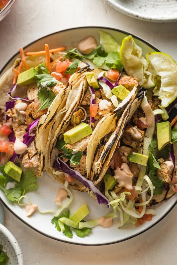 Close up image of Baja chicken tacos served with fresh toppings.