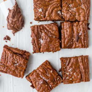 Close-up image of sea salt Nutella brownies with a small spatula dipped in the chocolate hazelnut spread.