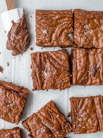 Close-up image of sea salt Nutella brownies with a small spatula dipped in the chocolate hazelnut spread.