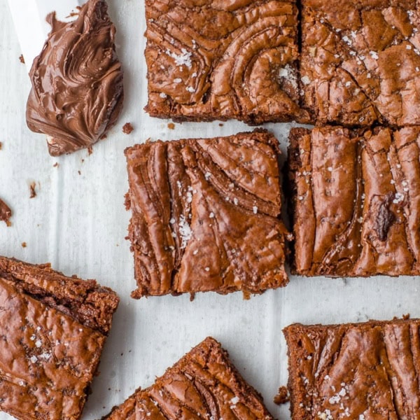 Close-up image of sea salt Nutella brownies with a small spatula dipped in the chocolate hazelnut spread.