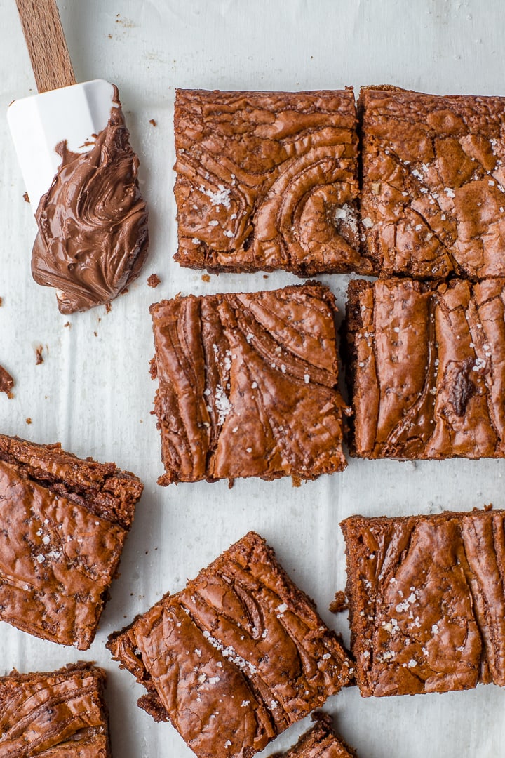 Close-up image of sea salt Nutella brownies with a small spatula dipped in the chocolate hazelnut spread.