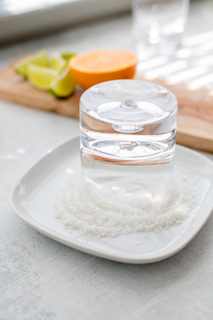 A cocktail glass being rimmed with salt.