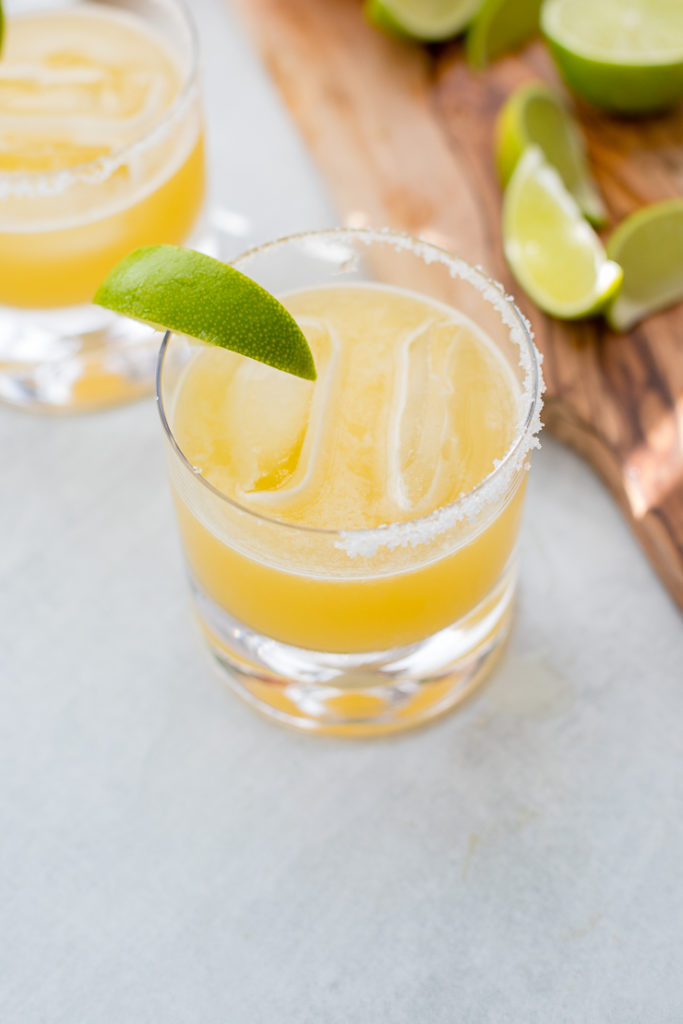 Two cocktail glasses filled with skinny margaritas and garnished with fresh lime.