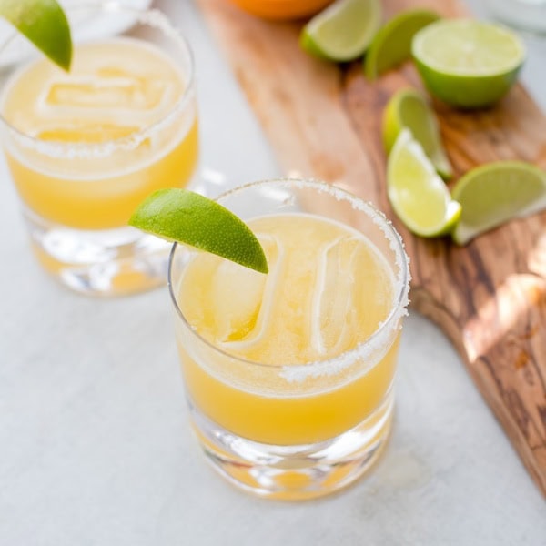 Two cocktail glasses filled with skinny margaritas and garnished with fresh lime.