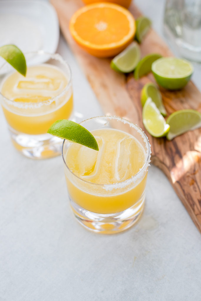 Two cocktail glasses filled with skinny margaritas and garnished with fresh lime.